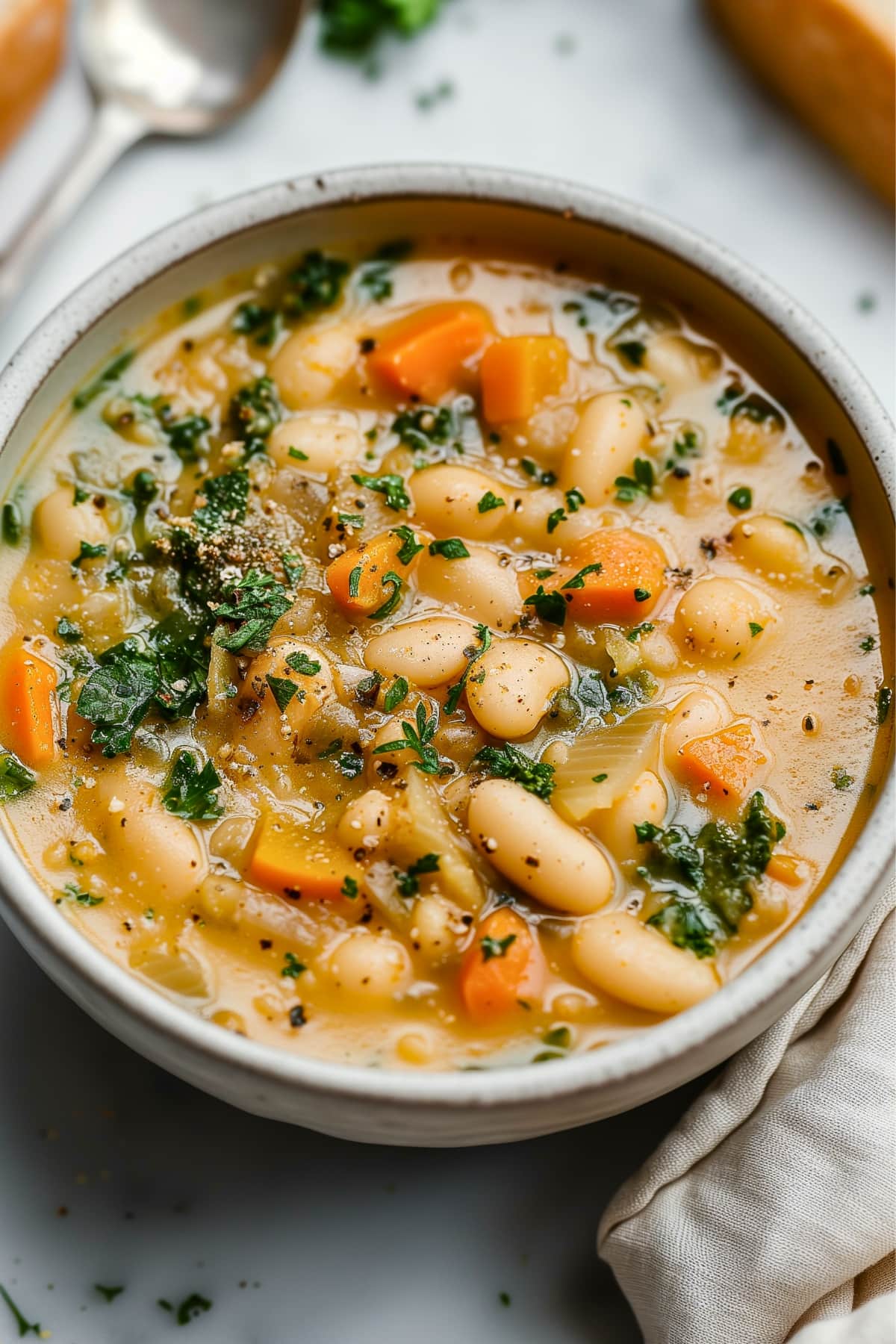 White bean soup with spinach and veggies in bowl.