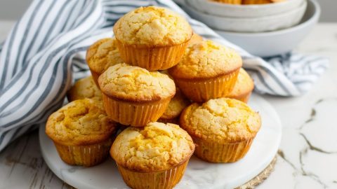 A bunch of cornbread muffins stacked on a white marble table