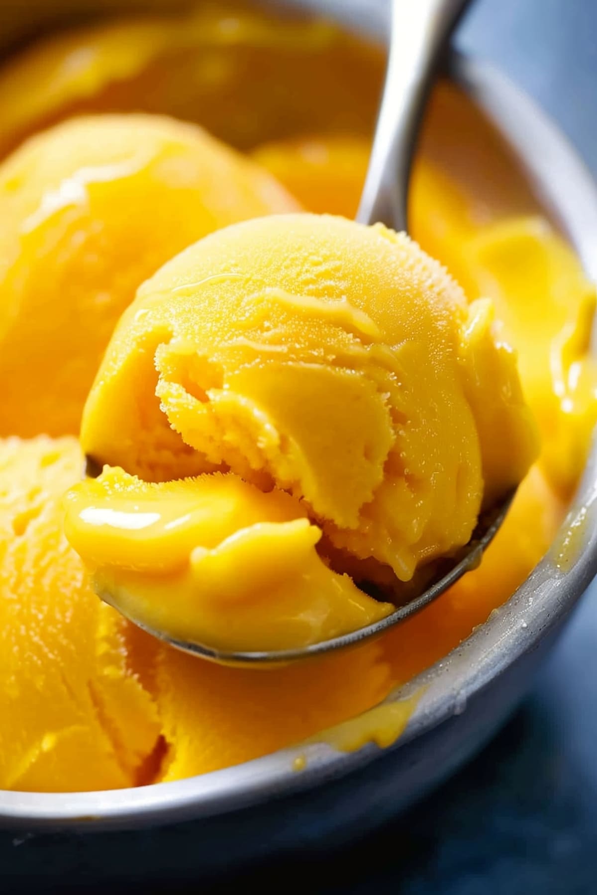 A bowl of mango sorbet with a spoon, close-up shot