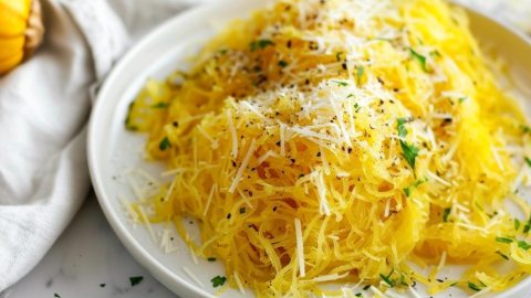 Shredded air fried squash served on a white plate garnished with parmesan cheese.