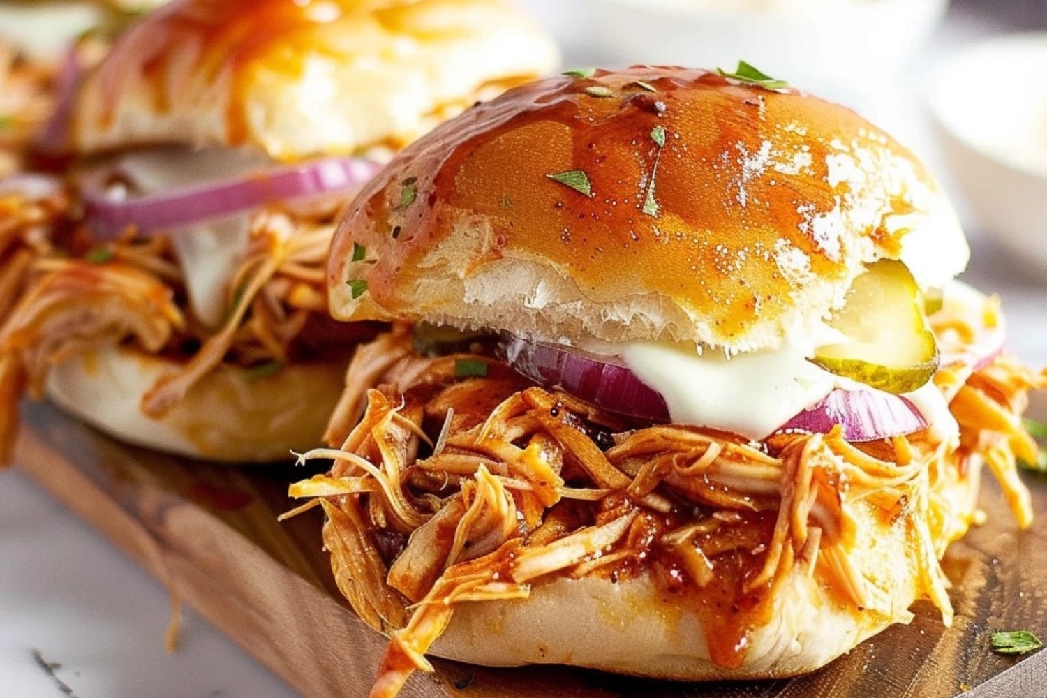 BBQ chicken sliders with melted cheese on a wooden board.