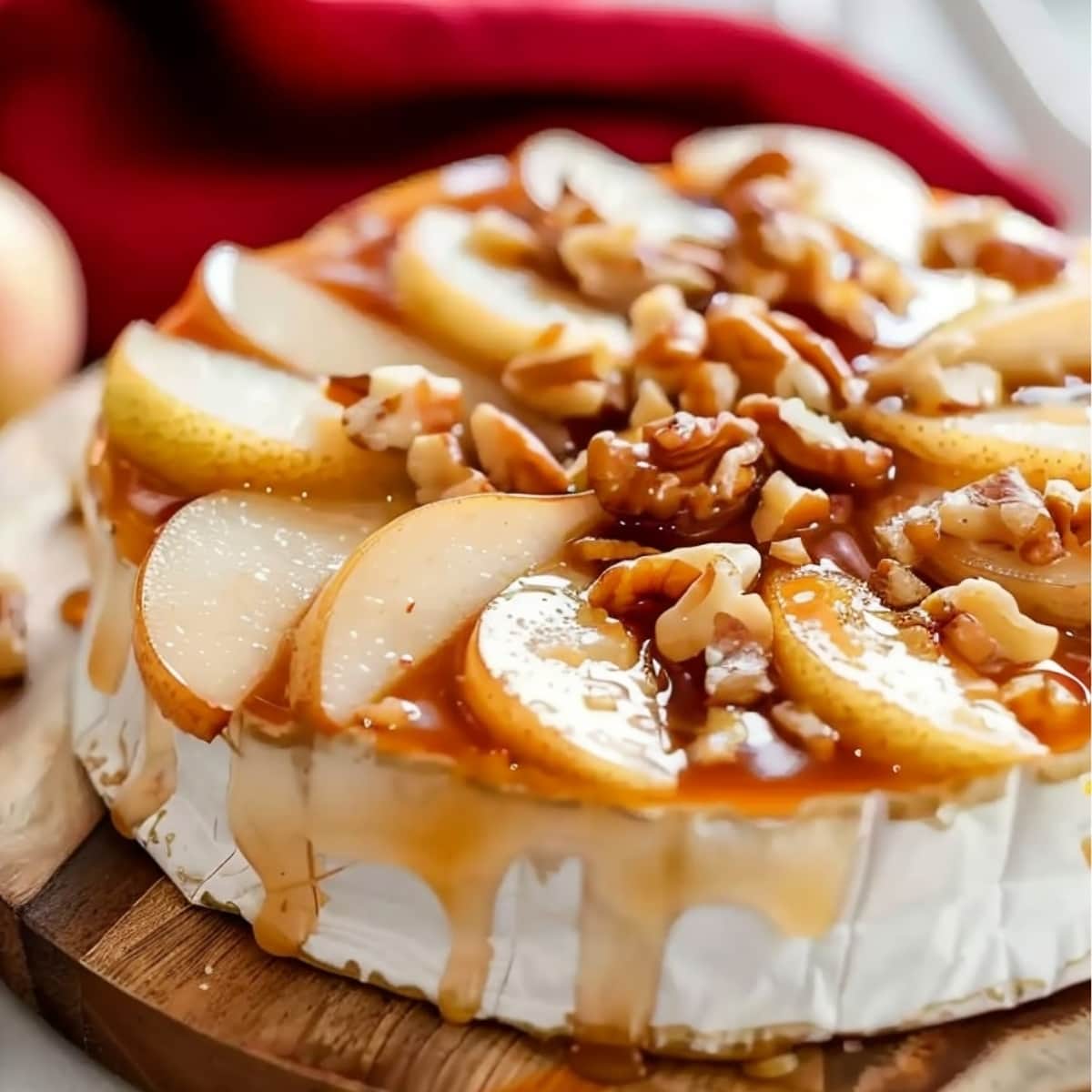 A round wheel of baked brie cheese topped with sliced pears and walnuts