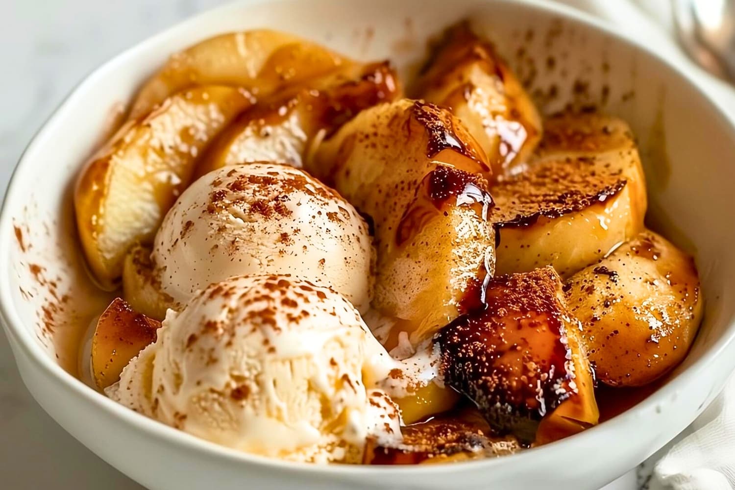 Baked apple slices served with vanilla ice cream on a white bowl.