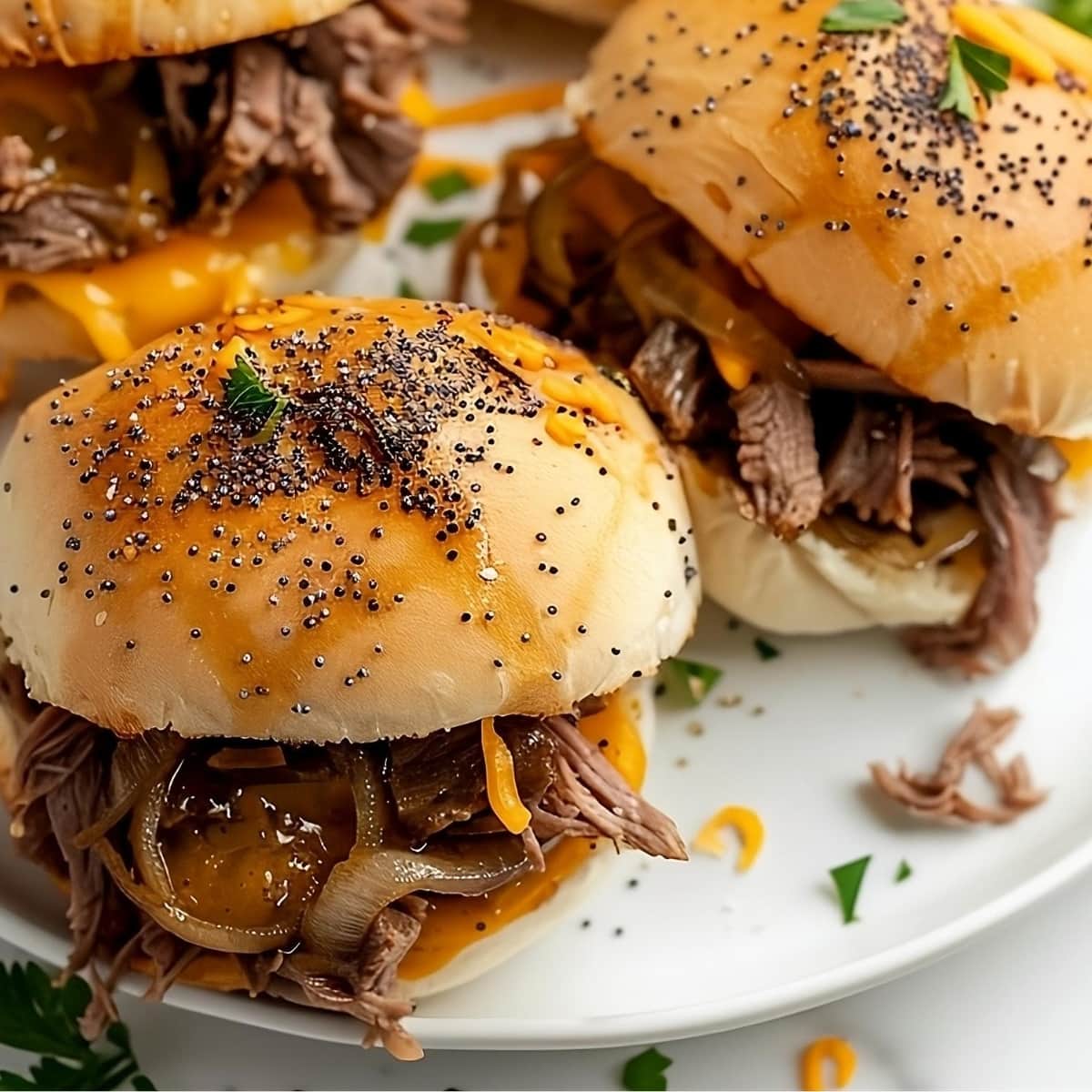 Cheese and beef sliders in a plate with poppy seeds butter on top.
