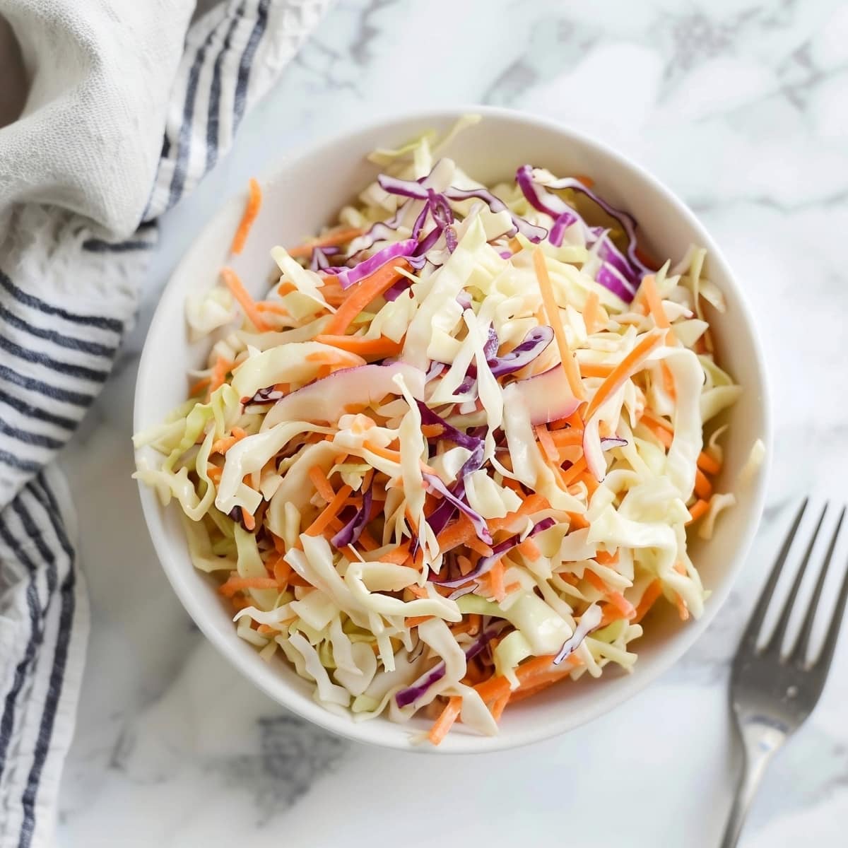 Coleslaw in a bowl on a white marble table