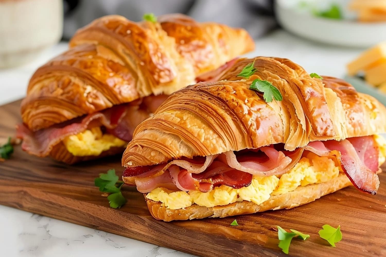 Breakfast croissant sandwich with bacon and egg in a wooden board