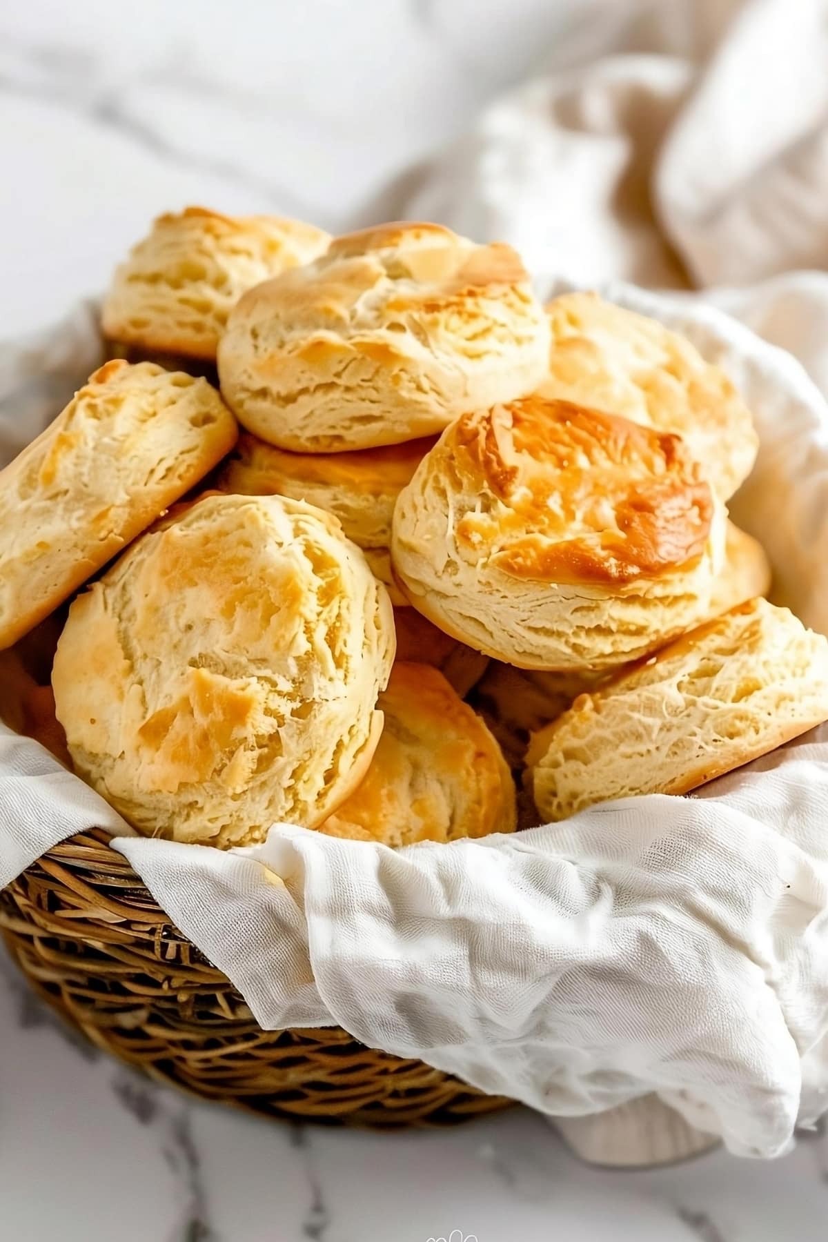 Bunch of air fried biscuits in a basket with cloth lining.