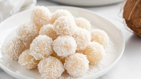Balls of dessert covered in coconut in a white plate.