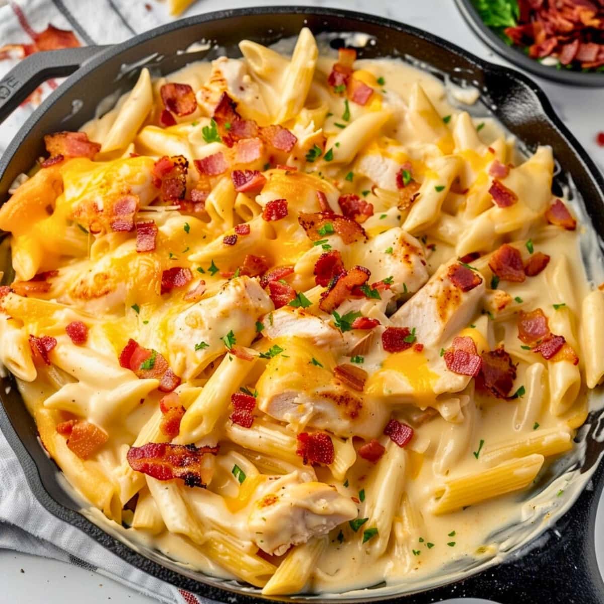 Cheesy and saucy crack chicken penne pasta in a cast iron skillet.