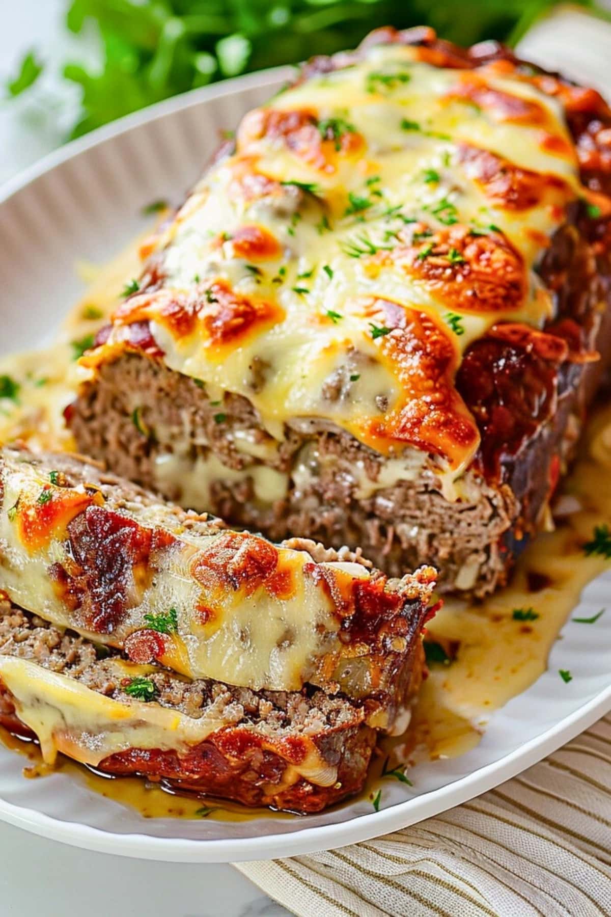 Sliced cheesy Philly Cheesesteak Meatloaf with melted cheese served on a white plate.