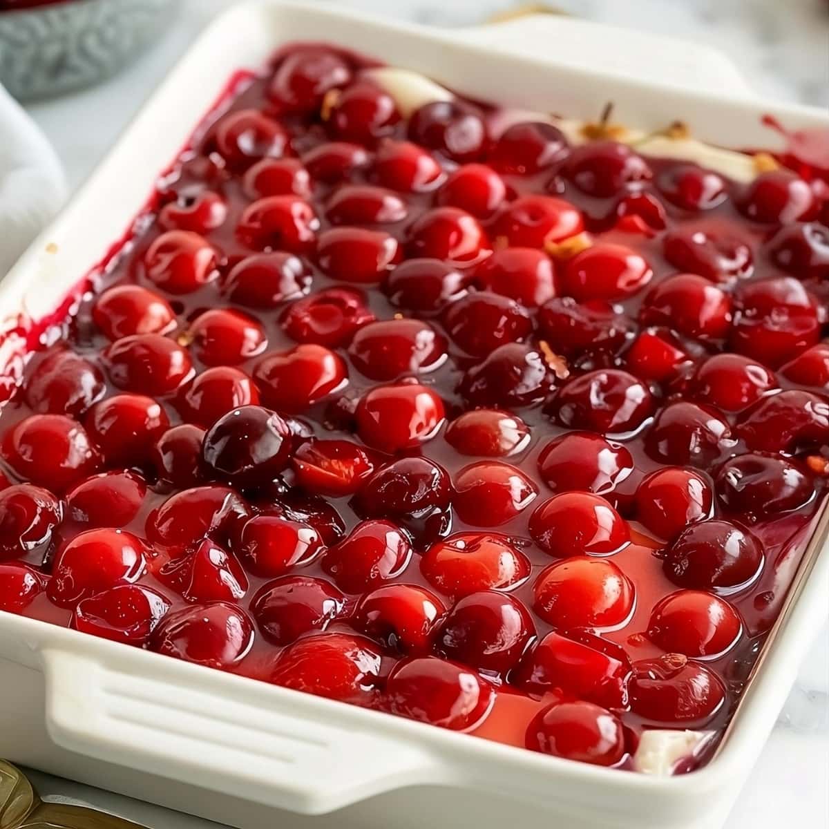 Cherry delight in a white baking dish on a white table.