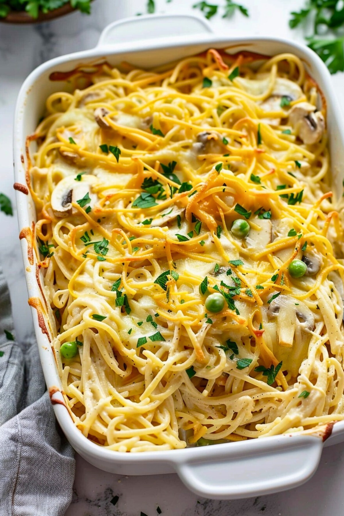 Baked chicken tetrazzini in a casserole dish garnished with chopped parsley.