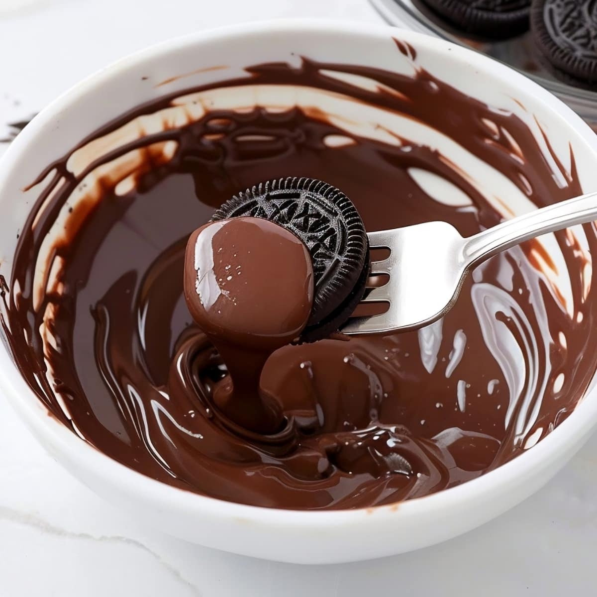 an oreo cookie being dipped into melted chocolate in a bowl