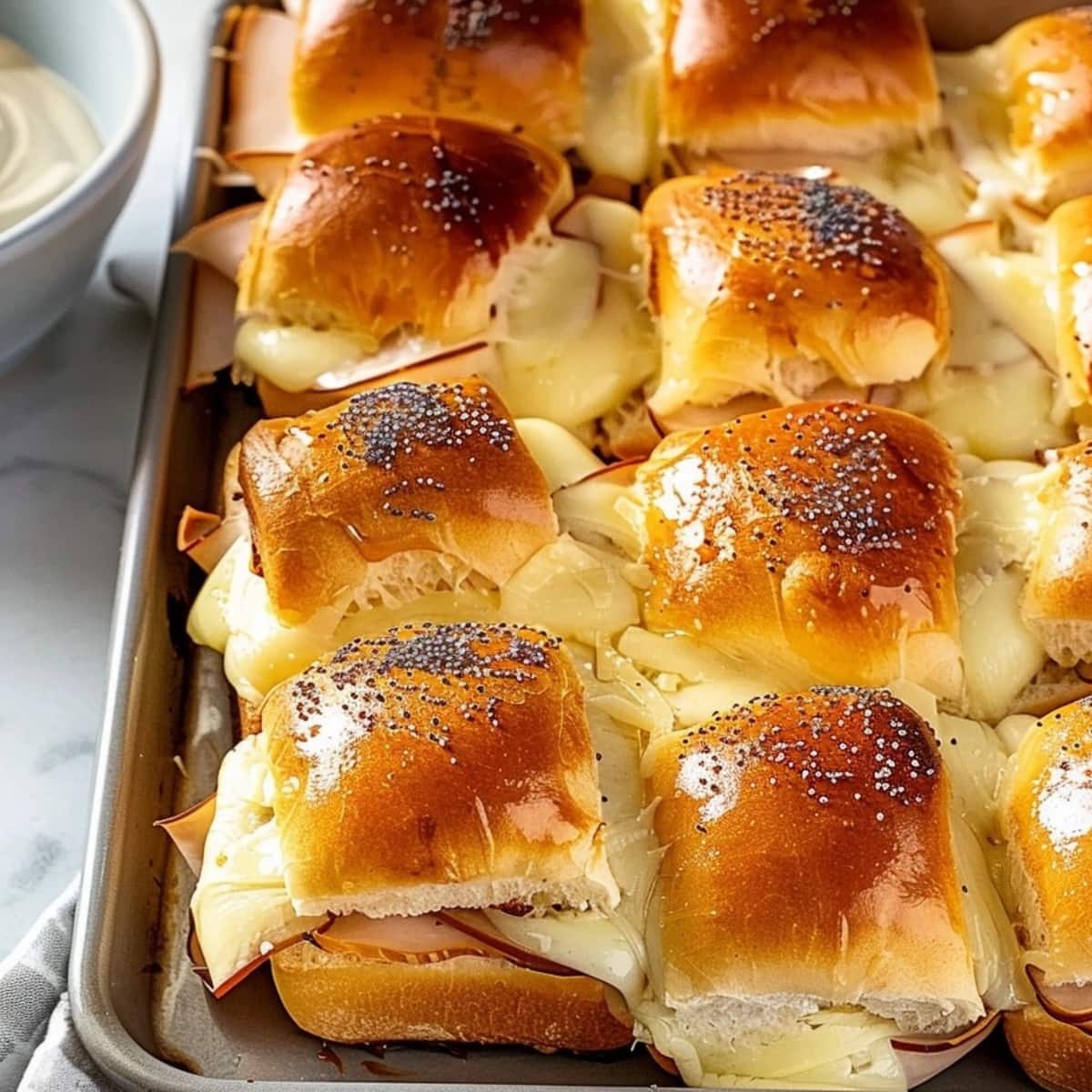 Slider rolls with turkey and cheese filling on a sheet pan.