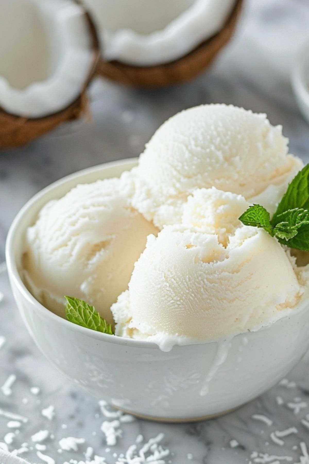 Coconut sorbet in a white bowl garnished with mint leaves.