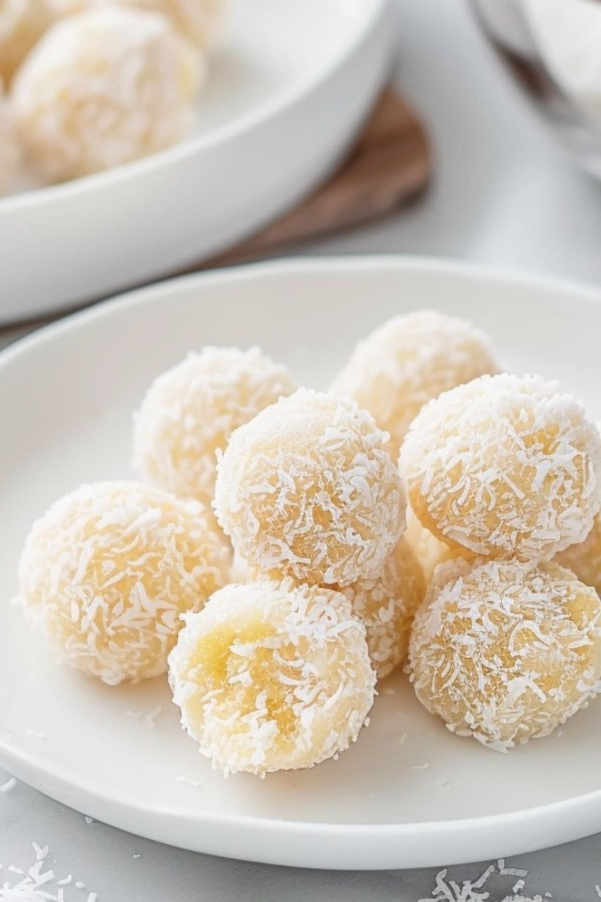 Shredded coconut coated dough balls in a white plate.