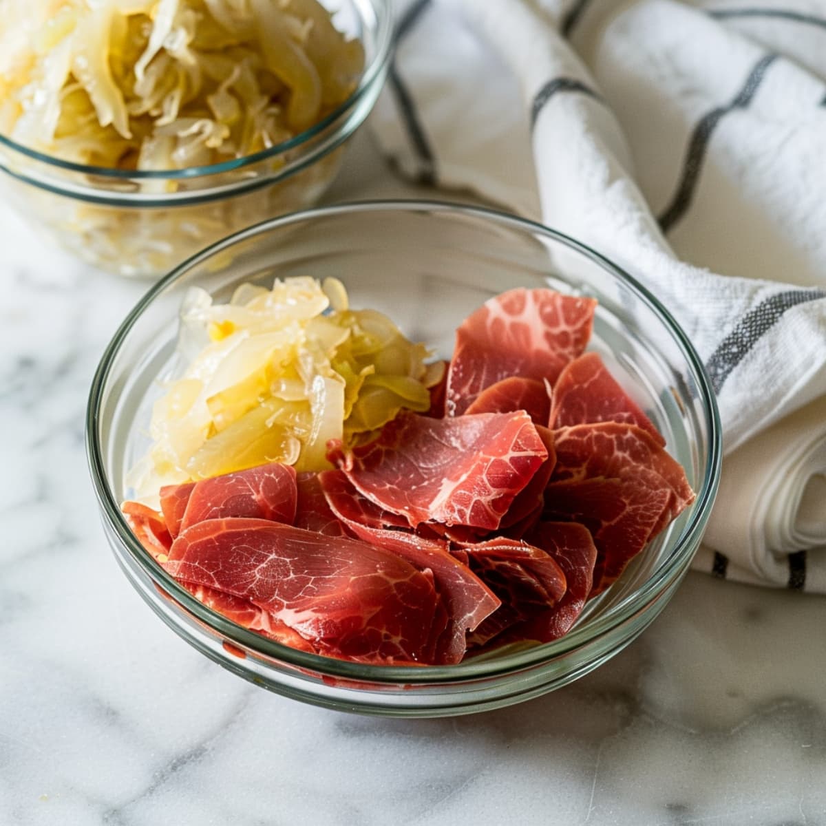 A glass bowl of raw corned beef and sauerkraut