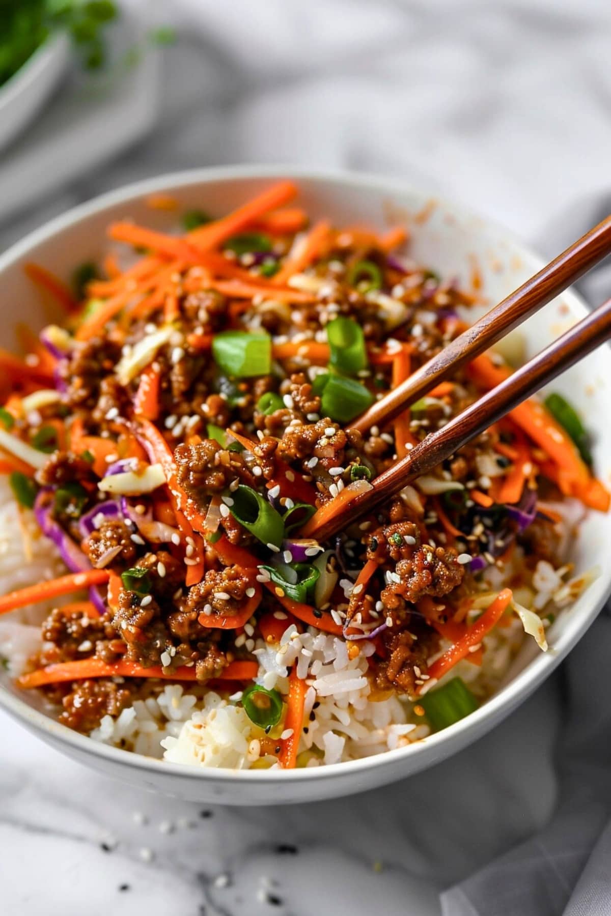Crack slaw topped in a white rice on a bowl with chopsticks.