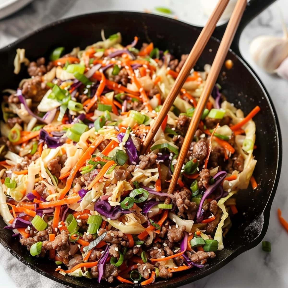 Crack slaw in a cast iron pan tossed with a chopstick.