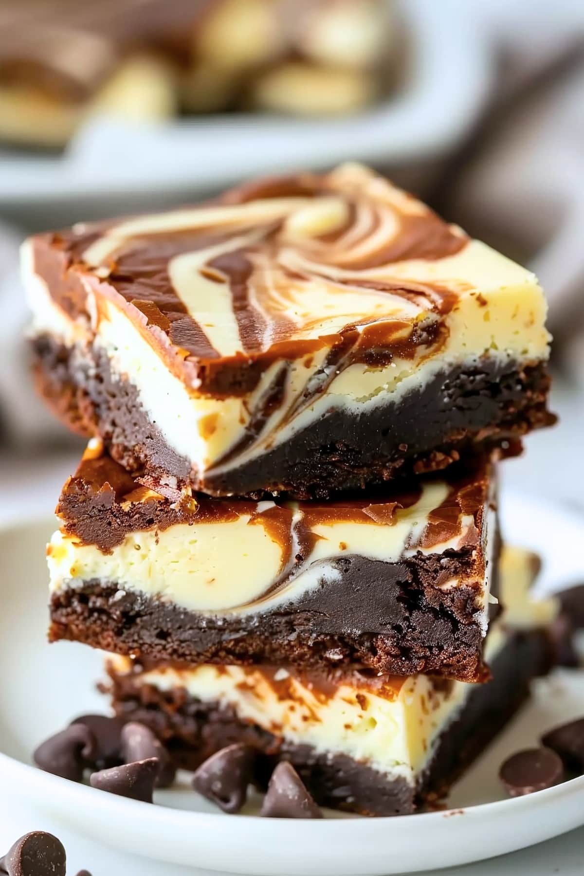 A stack of homemade cream cheese brownies sitting in a white plate