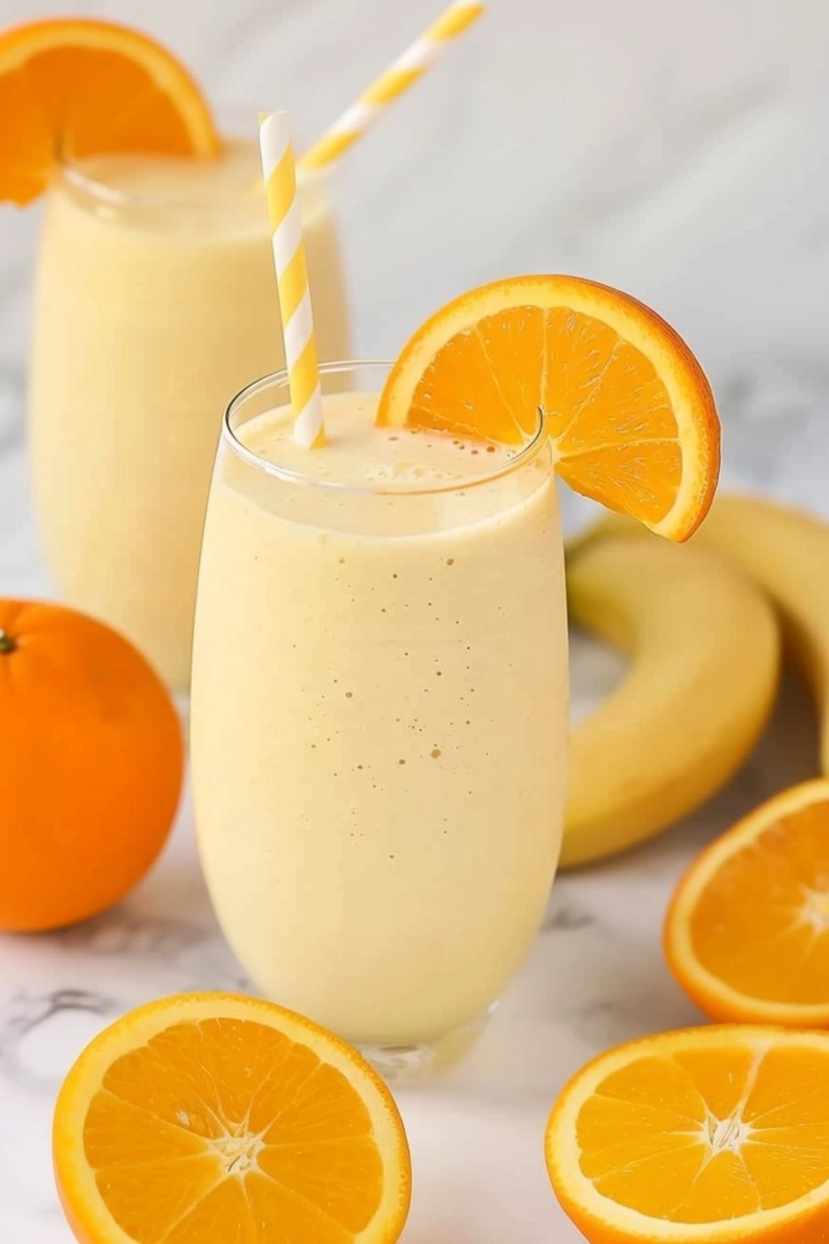 Orange creamsicle smoothie in a tall glass with orange slice garnish.