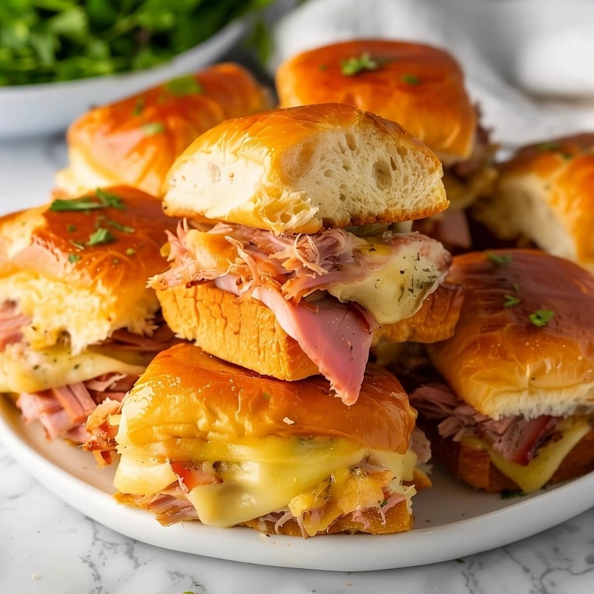 Stack of pulled apart Cuban sliders in a white plate.