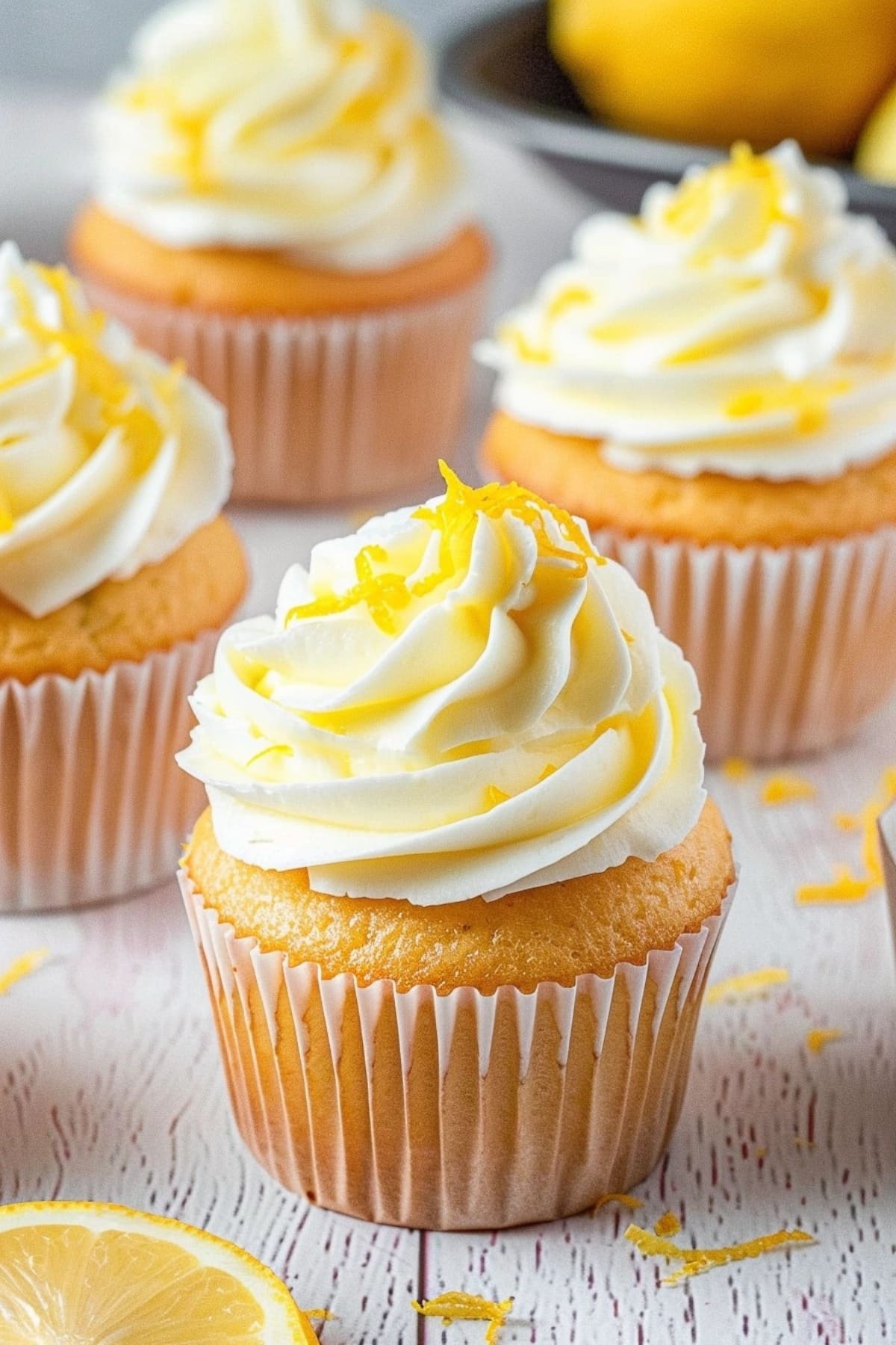 Cupcakes topped with lemon whipped cream garnished with lemon zest.