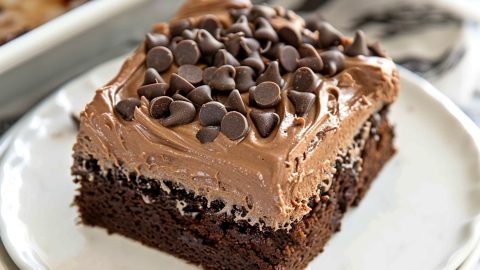 Chocolate poke cake topped with creamy mousse in a white plate