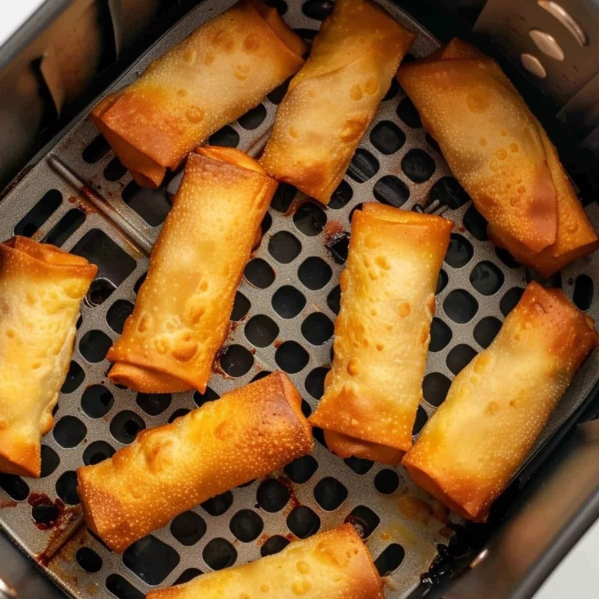 Egg rolls inside an air fryer basket.