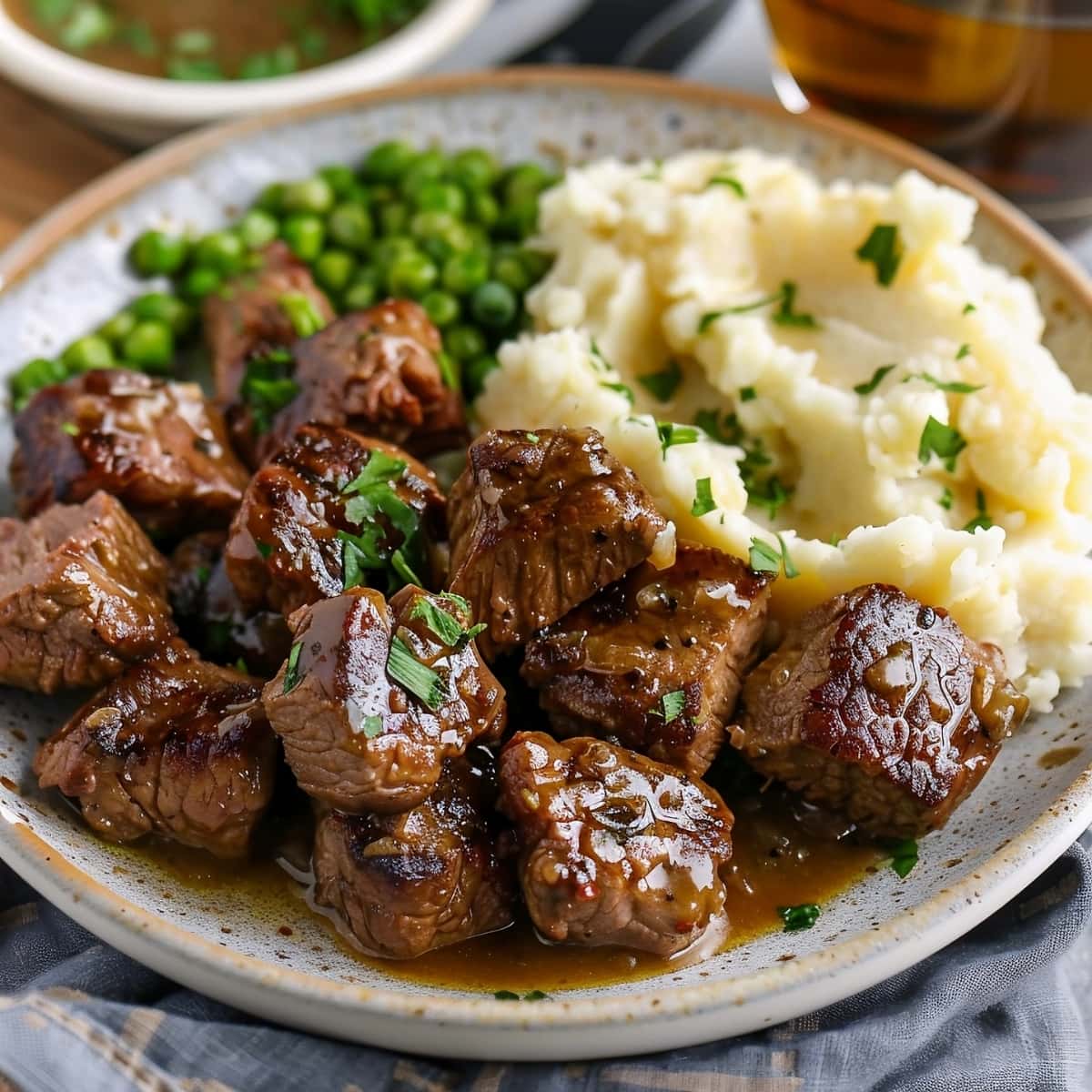 Homemade garlic butter steak bites served with mashed potates and green peas