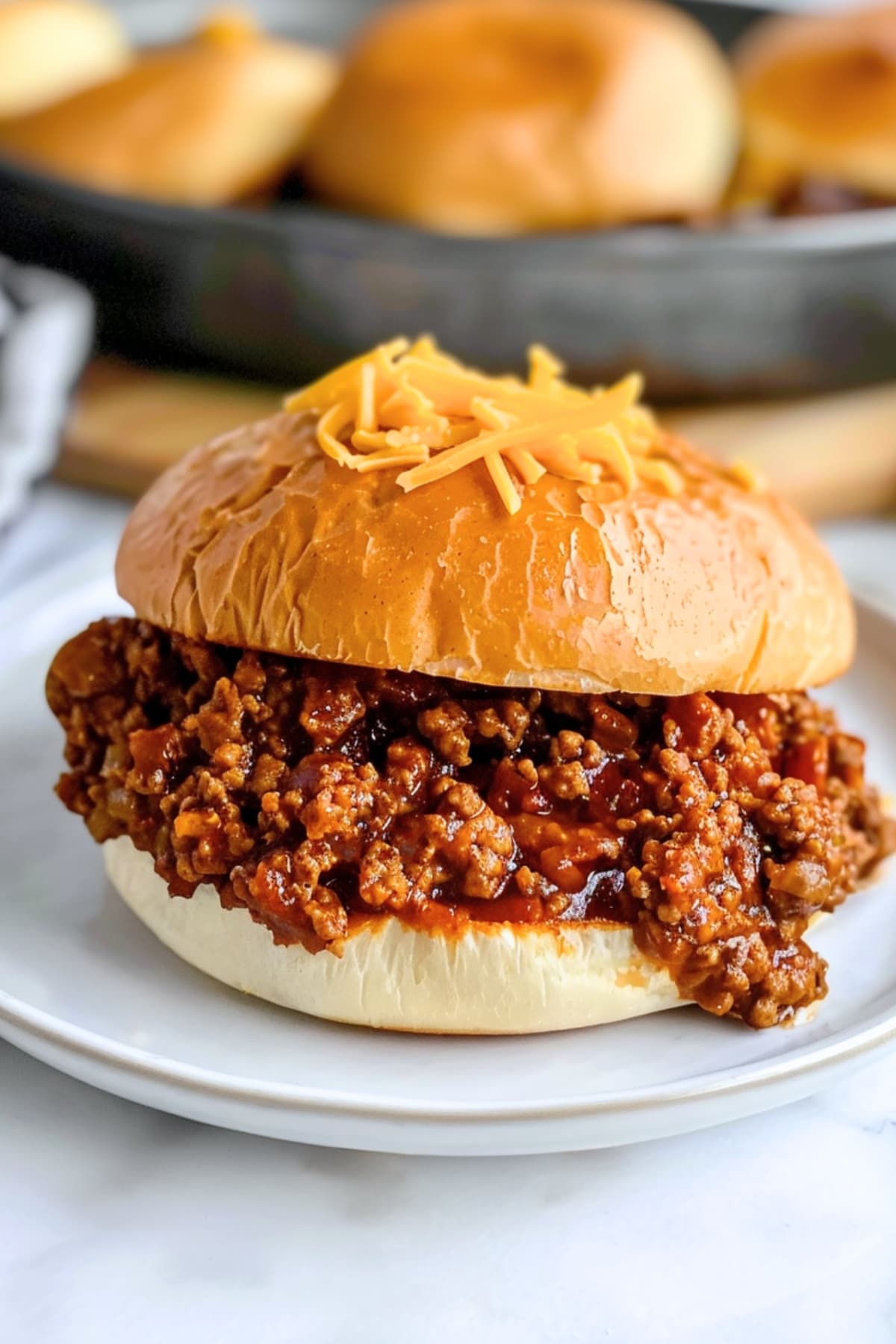 Homemade barbecue sloppy joes with green bell pepper and onions, topped with shredded cheese, bursting with smoky flavor and tangy sauce