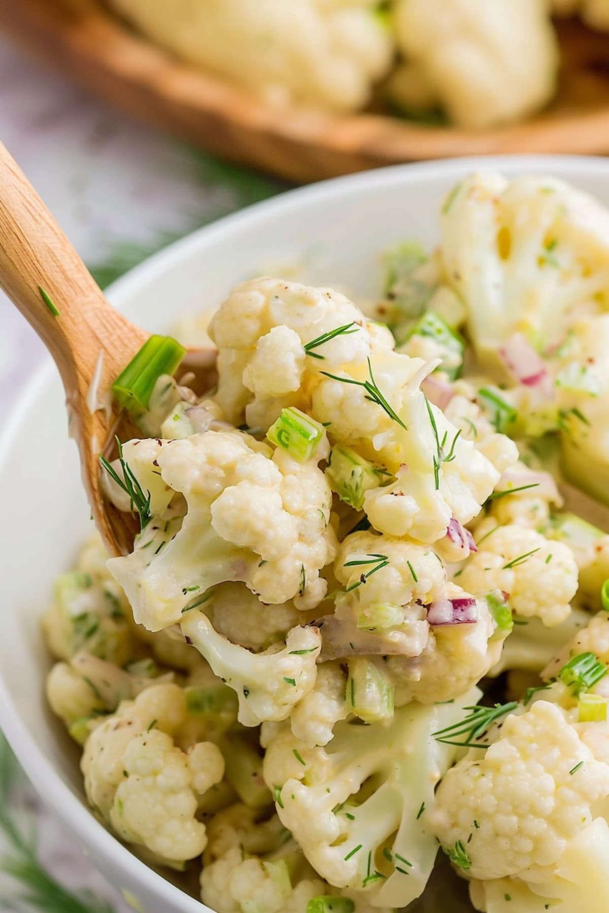 A bowl of healthy cauliflower potato salad with dill and red onions