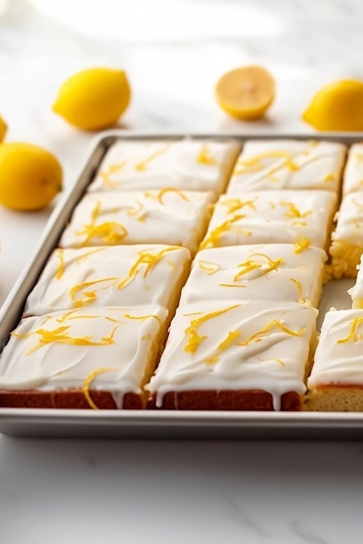 Lemon sheet cake sliced with lemon zest garnish and white glaze on top.