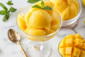 Homemade cold and refreshing mango sorbet in a glass with mint