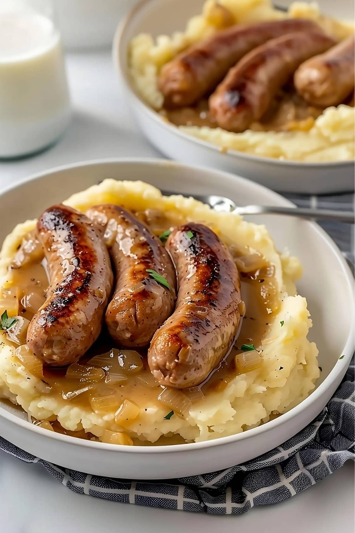 Mashed potato in bowls topped with sausage and onion gravy.