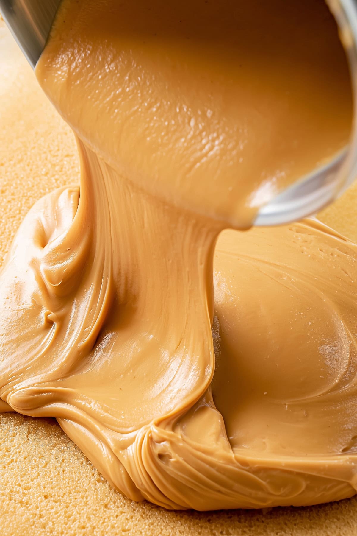 Peanut butter being spread over a peanut butter sheet cake.