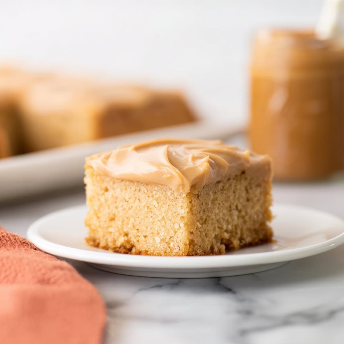 A square slize of peanut butter sheet cake with creamy frosting.
