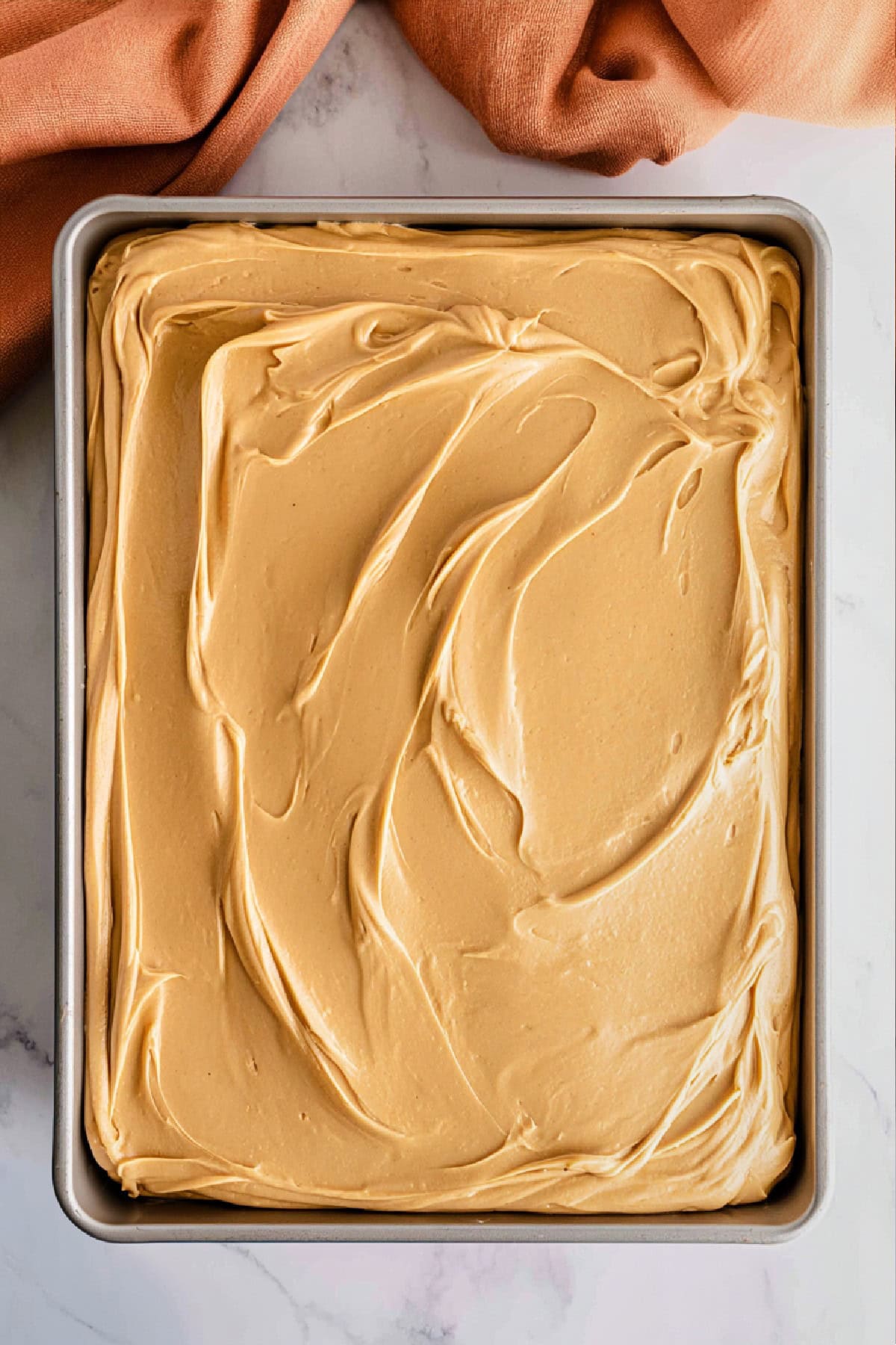 An overhead view of peanut butter sheet cake in a pan.