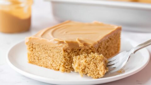 Slice of peanut butter sheet cake with creamy frosting on a white plate.
