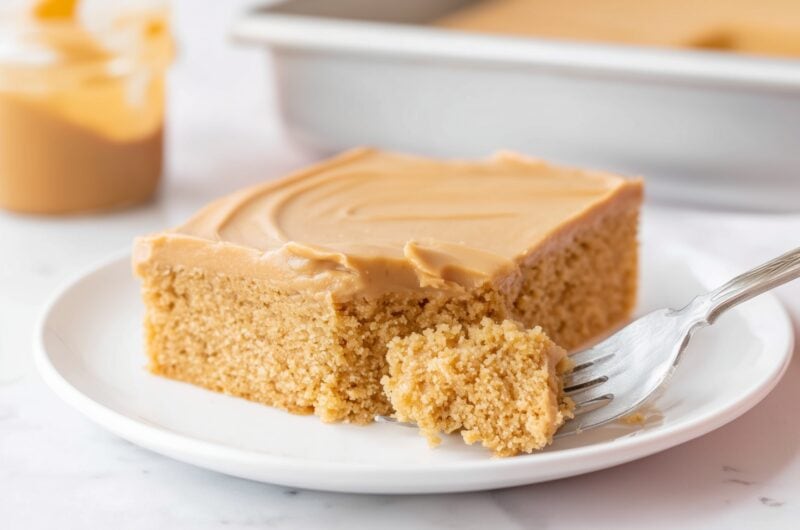 Slice of peanut butter sheet cake with creamy frosting on a white plate.
