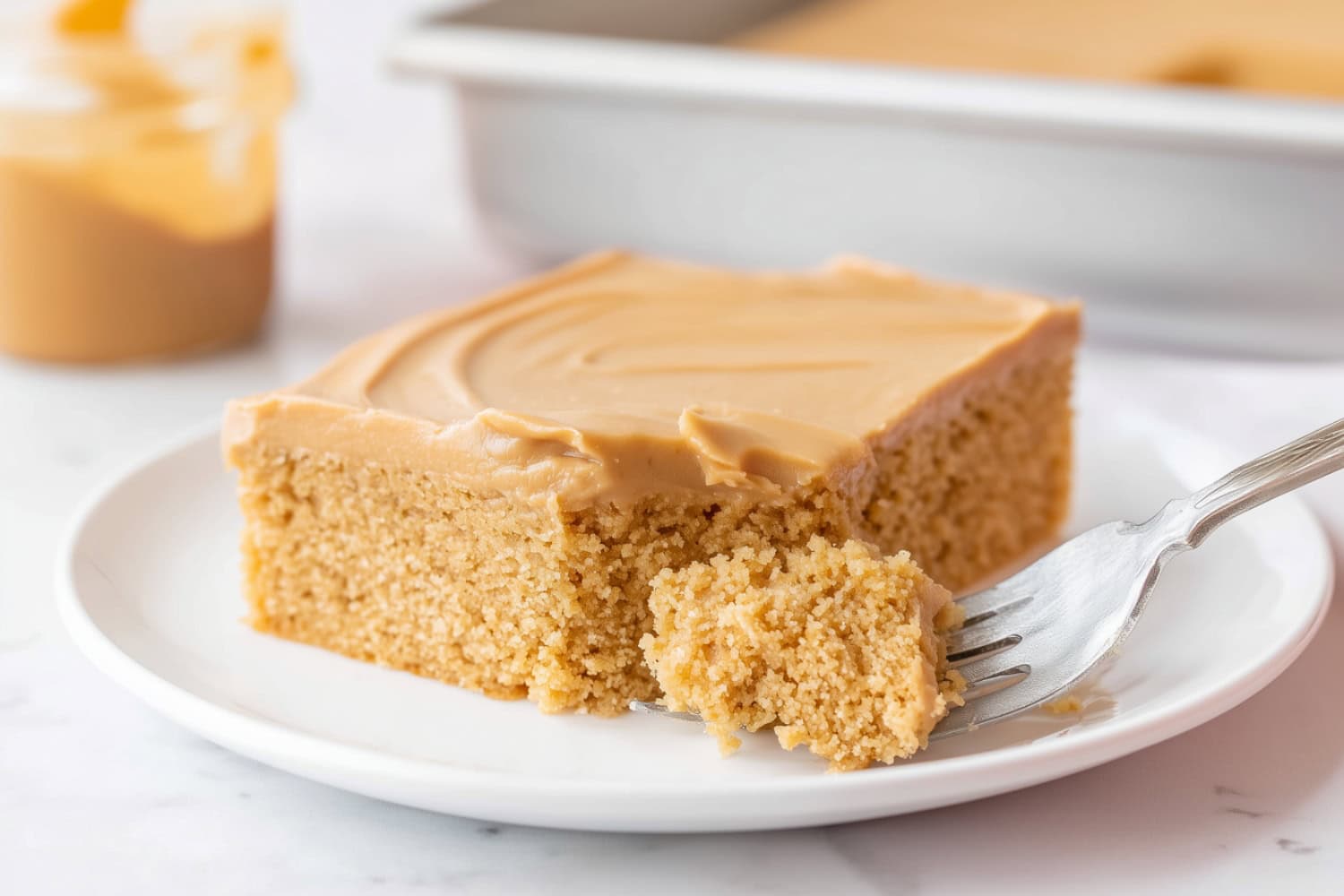 Slice of peanut butter sheet cake with creamy frosting on a white plate.