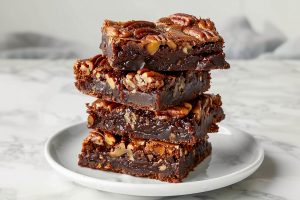 Homemade chocolate pecan pie brownies stacked in a clean white plate