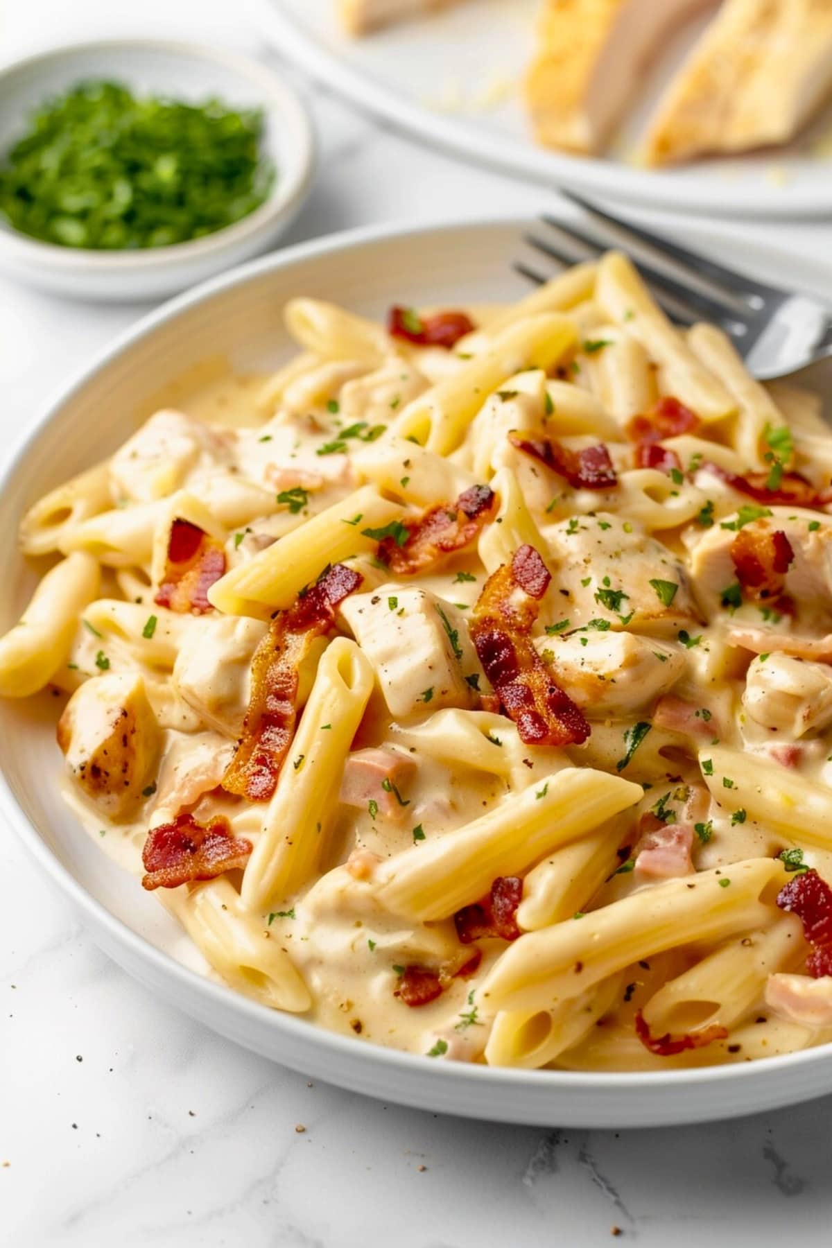 Creamy crack chicken penne pasta served in a white plate.