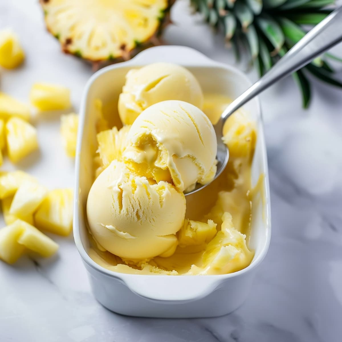 Scoops of pineapple sorbet in a white container