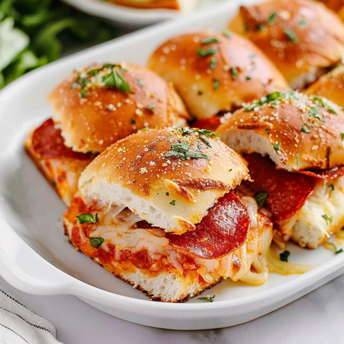 Cheesy pizza sliders with pepperoni, topped with herbs