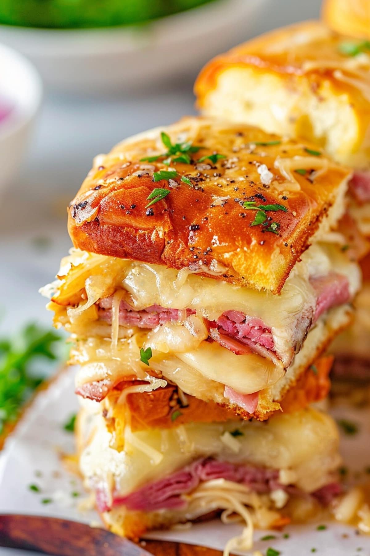 A stack of reuben sandwich with cheese and sauerkraut topped with poppy seeds