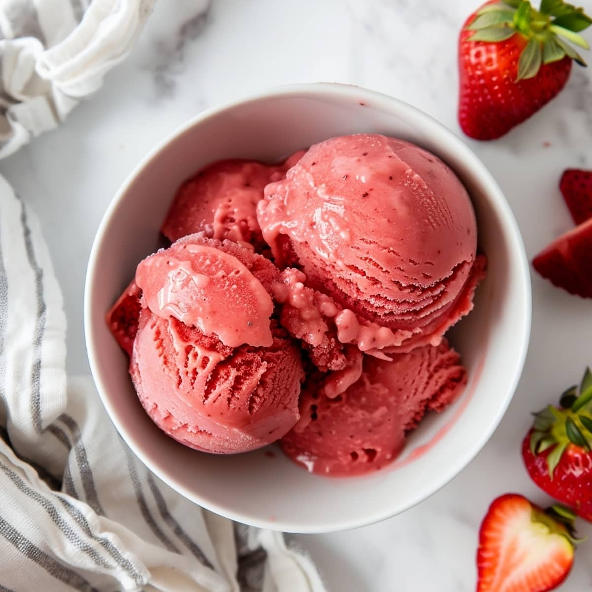 Scoops of sweet red strawberry sorbet in a bowl, overhead view
