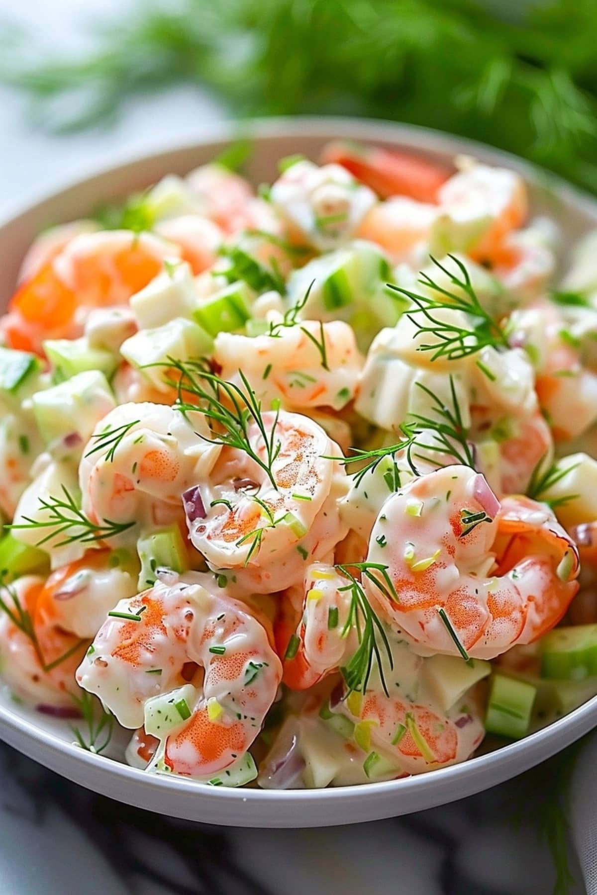 Shrimp salad with chopped celery, onion and mayonnaise dressing in a white plate garnished with dill.