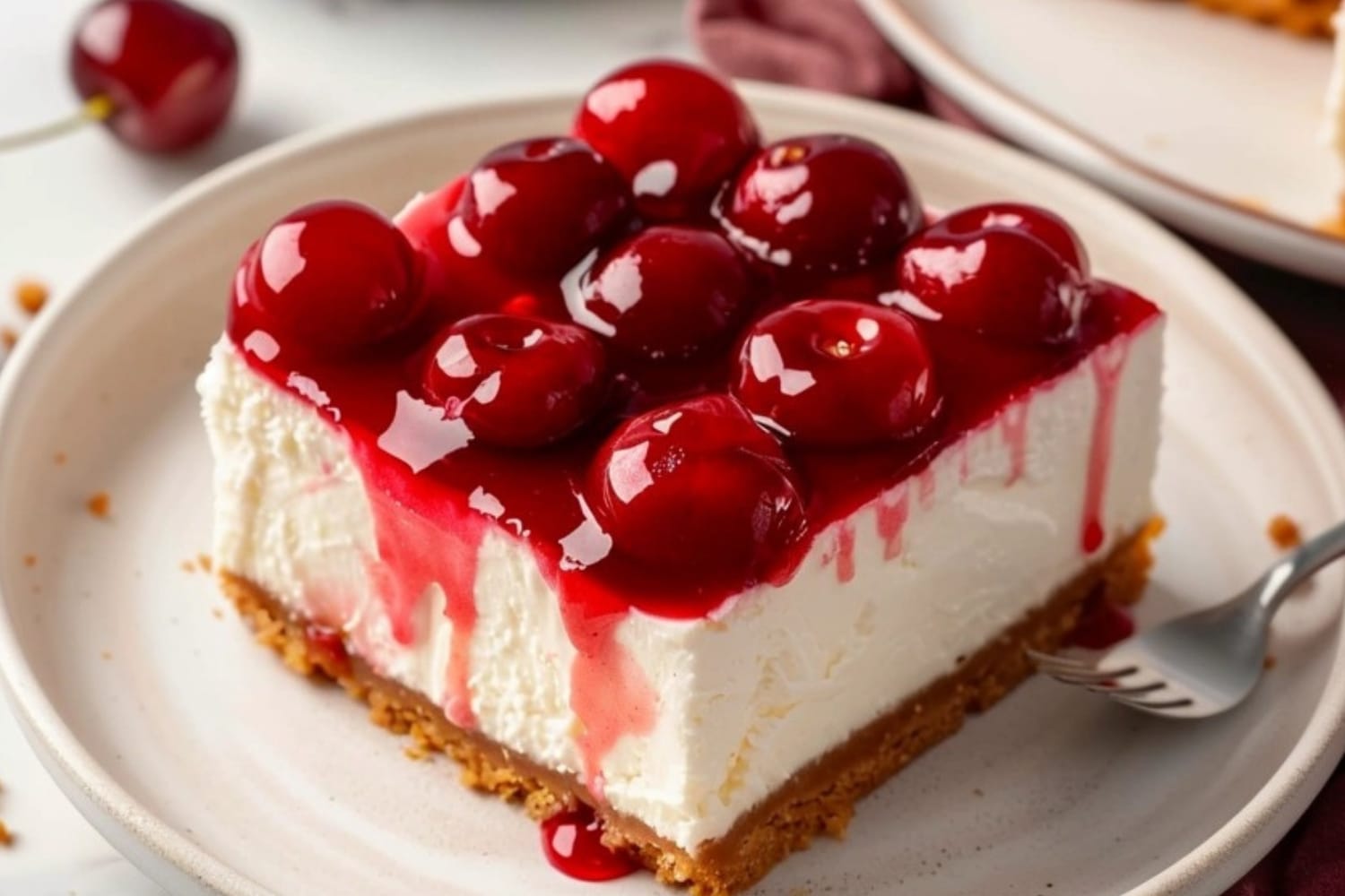 A slice of cherry delight in a white plate with fork on the side.