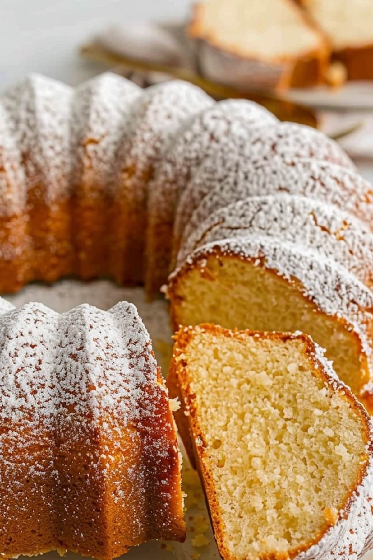 Buttermilk pound cake dusted with powdered sugar, portion sliced.